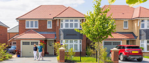 Modern semi-detached houses with red-tiled roofs, front gardens, a tree, and a red Range Rover parke