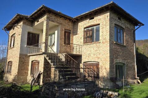 Exterior view of a two-storey brick house featuring wooden shutters and an iron-railed external staircase.