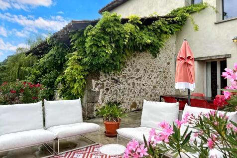 A charming patio features white seating, a red-pat