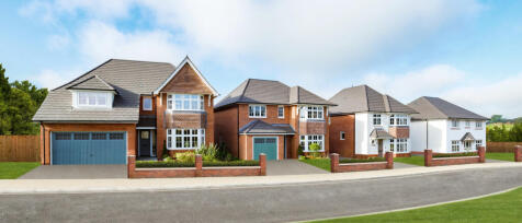 A row of modern detached houses with brick and white exteriors, front gardens, and driveways under a