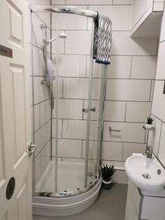 Modern tiled bathroom with a curved glass showe...