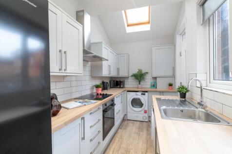 Bright, modern galley kitchen with white cabine...
