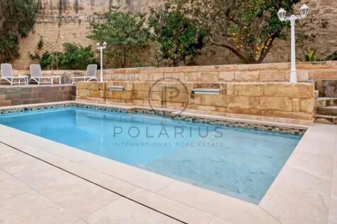 A small outdoor pool surrounded by stone walls, wi