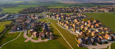 Modern residential houses with brick and timber cladding, surrounded by green lawns and trees under