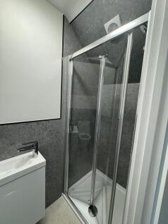 Modern compact bathroom with a corner shower en...