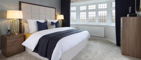 Elegant bedroom with large bay window, bright modern decor, with gold bedside lamps and a decorative