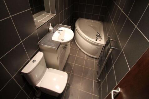 A modern bathroom suite featuring a corner bath...