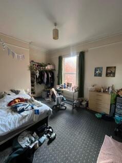 A cozy bedroom with a single bed, cluttered but...