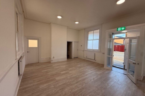 The front of an arch, with a fully glazed frontage and door allowing you to see into the arch interior.