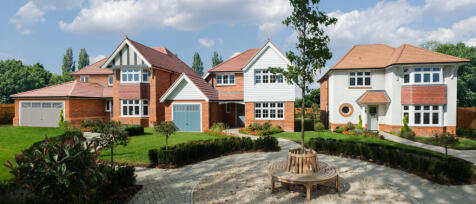 Two modern detached houses with well-maintained gardens and a circular seating area with a tree in t