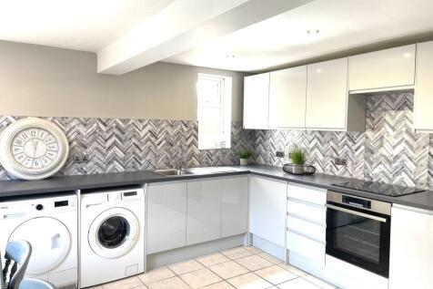 Modern kitchen with white cabinetry, stylish ba...