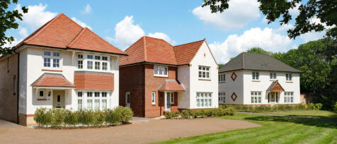 Three modern detached houses with red-tiled roofs, white walls, and well-maintained gardens under a