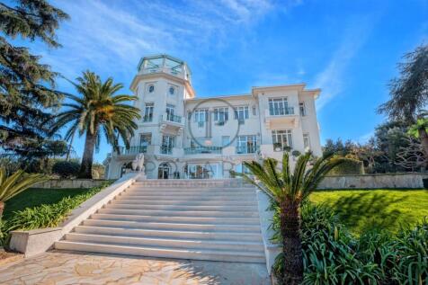 A grand, white mansion with a tower and palm trees