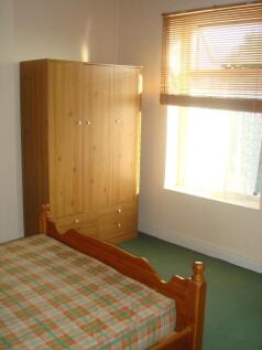 A cozy bedroom featuring a wooden bed frame wit...