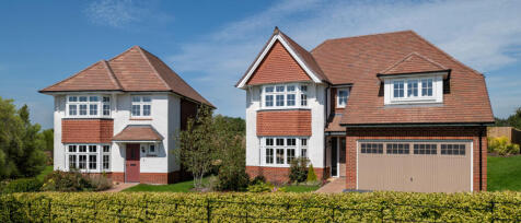 Modern two-storey house with white walls, red brick accents, and a gabled roof, surrounded by well-k