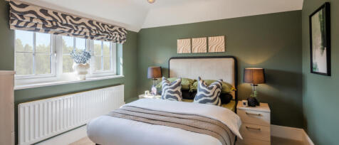 Redrow spacious bedroom with sage green walls and double bed with side units and lamps