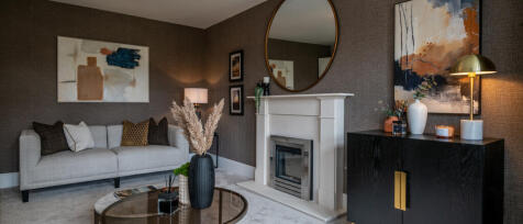 Modern living room with a white sofa, abstract artwork, a fireplace, and decorative items including