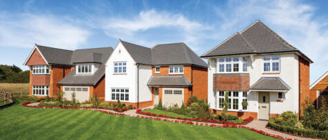 Row of modern detached houses with manicured lawns and colourful flower beds under a blue sky in Gil