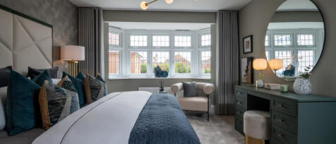 Modern bedroom with large bay window, stylish bed with multiple pillows, and elegant green dresser w