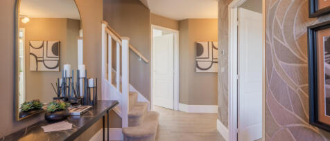 Stylish hallway design featuring large staircase and decorative table with wall mounted mirror