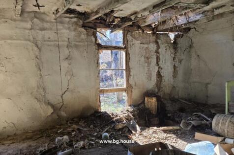 Room interior showing significant wall damage, barred windows, and debris on the floor