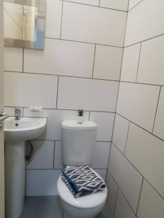 Compact, modern WC with white tiled walls, pede...