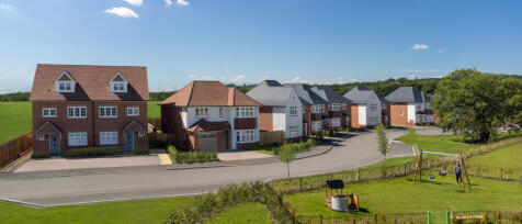 Newly built suburban houses with front gardens, a curved road, and a grassy area with a swing set un